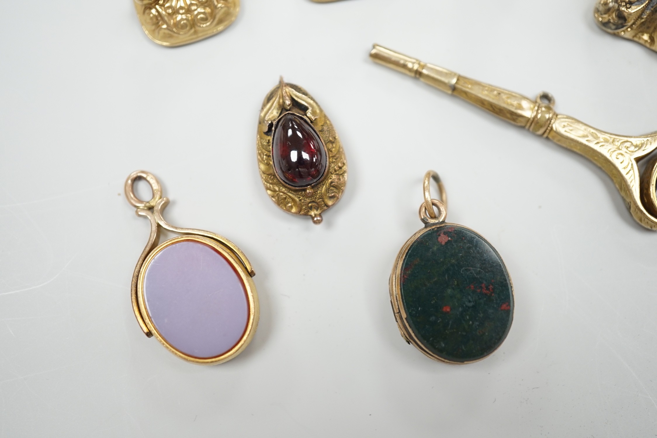 Four assorted 19th century and later yellow metal overlaid and gem set fob seals, a Victorian 15ct gold and sardonyx spinning fob, a sardonyx set locket, damaged pendant and yellow metal and two stone set watch key.